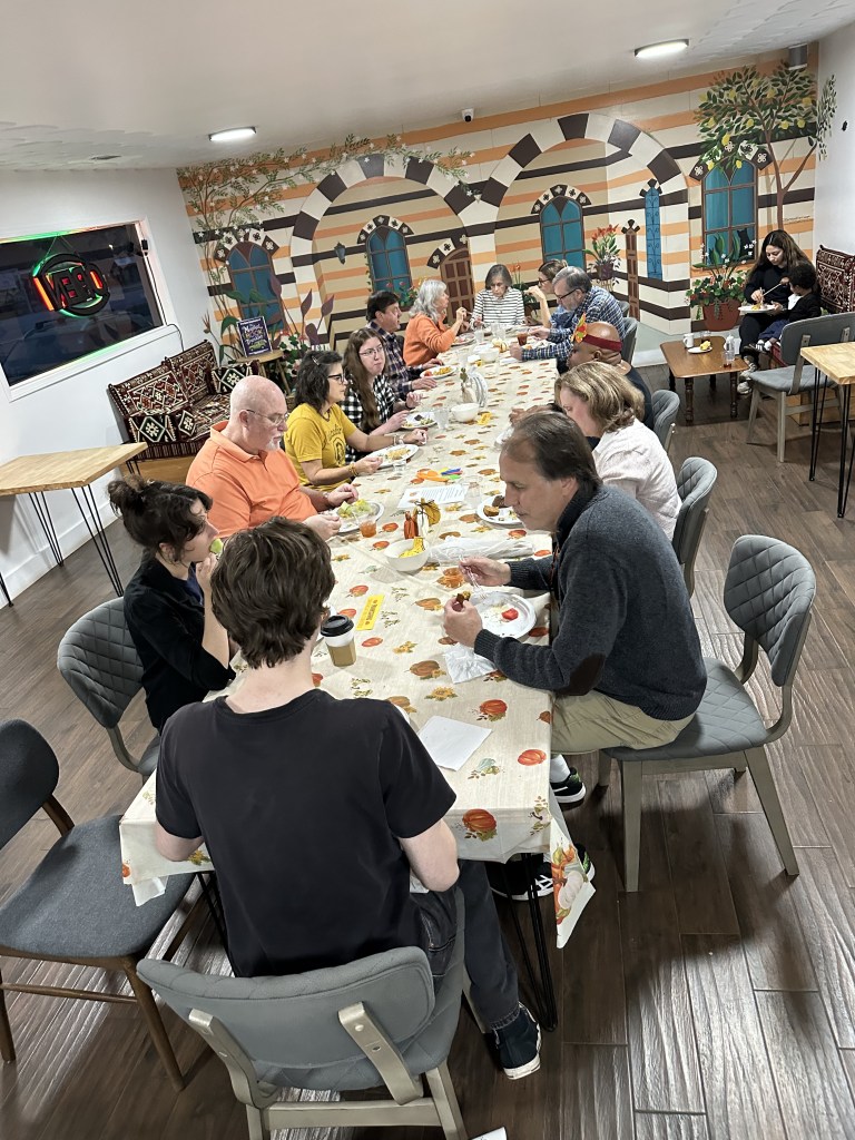 Everyone enjoying delicious food at Mint Coffeehouse's Thanksgiving Community Potluck