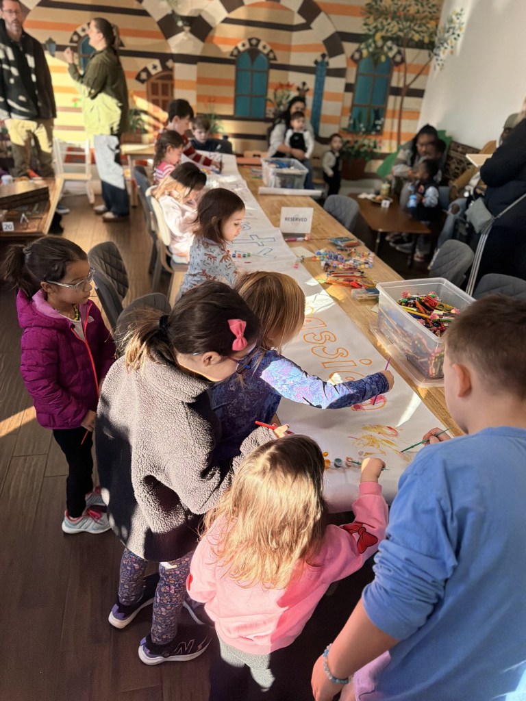 Community children creating a poster encouraging unity during Mint Coffeehouse's MLK Day event